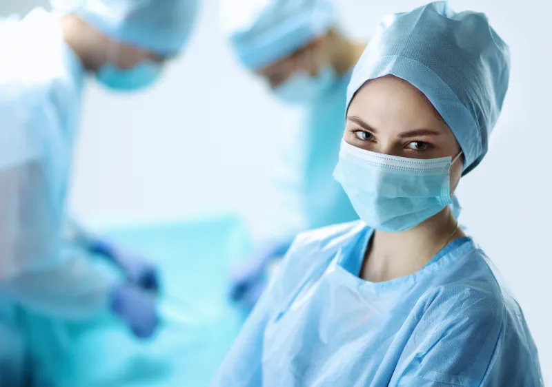 A surgeon in a mask and scrub cap