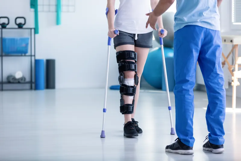 A person with a leg brace walking on crutches