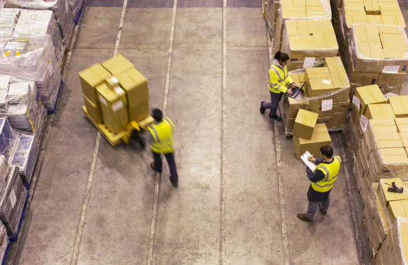Warehouse workers in safety vests moving pallets
