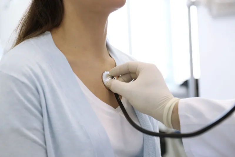 A clinician listening to a patient's chest with a stethoscope