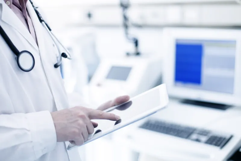 A doctor using a tablet at a computer station